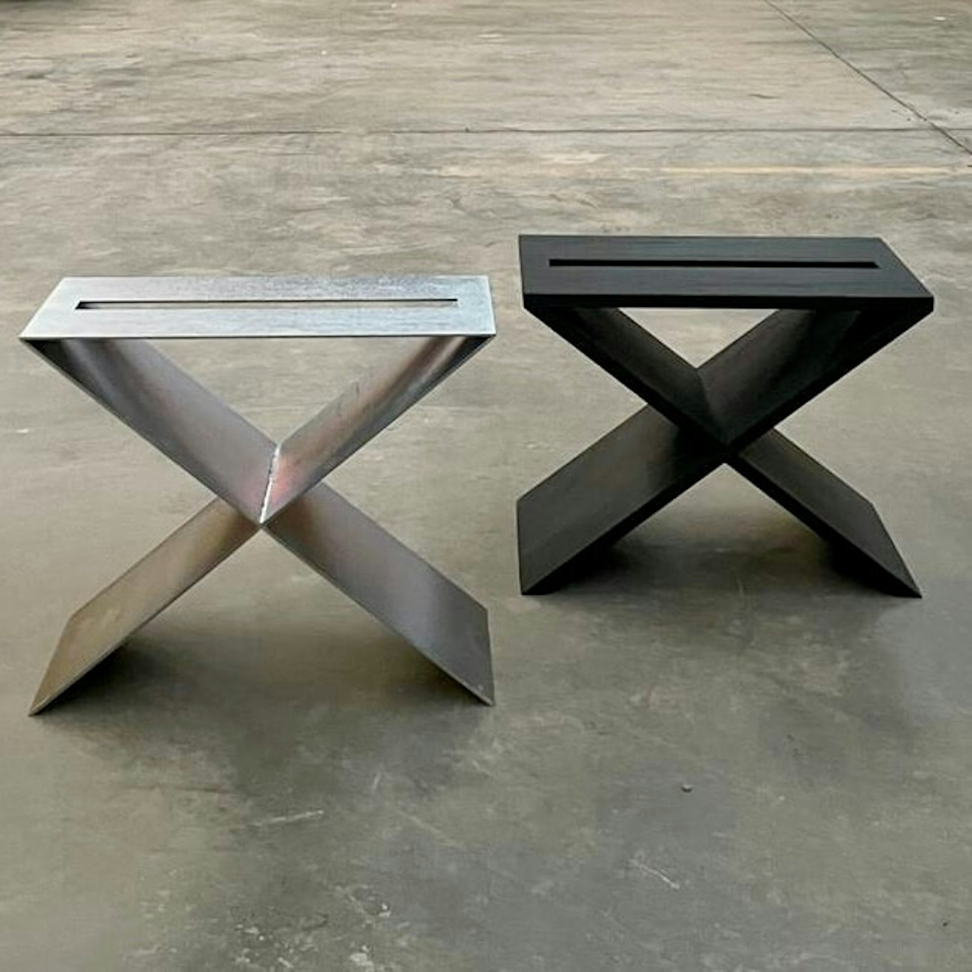 2 chairs, one steel and one wood, on a concrete floor